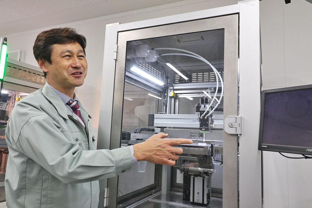 ドイツのInnovatiQ社(旧German RepRap社)製の LiQ320 と説明を行うホッティーポリマー社堀田社長
