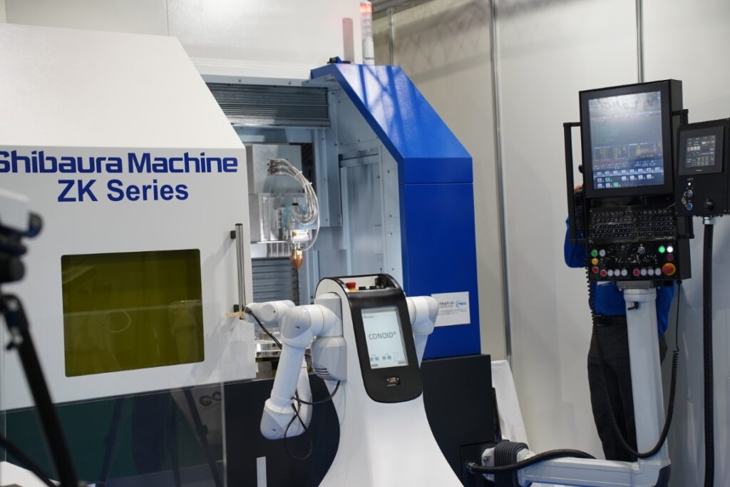 芝浦機械の金属AM造形機から二本腕ロボットがワークを取り出し、3次元測定器にセットするデモの様子